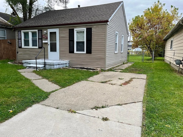 bungalow-style house with a front lawn, fence, and roof with shingles