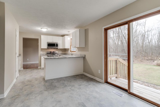 kitchen with sink, light stone counters, kitchen peninsula, white cabinets, and appliances with stainless steel finishes