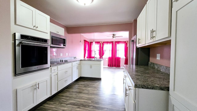 kitchen with appliances with stainless steel finishes, decorative light fixtures, white cabinetry, and dark hardwood / wood-style floors