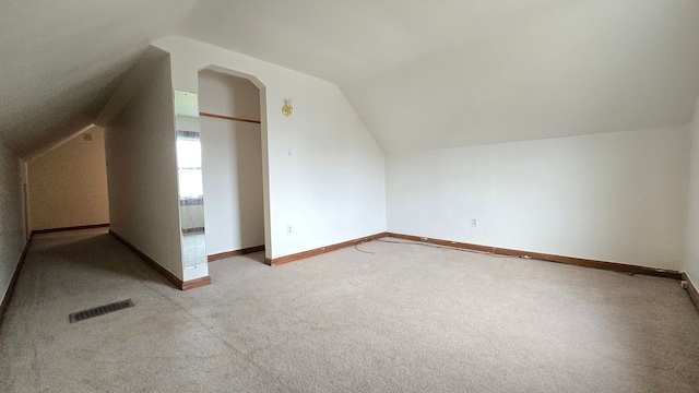 bonus room with light colored carpet and lofted ceiling