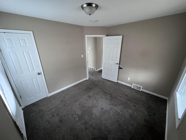 unfurnished bedroom featuring dark colored carpet and a closet