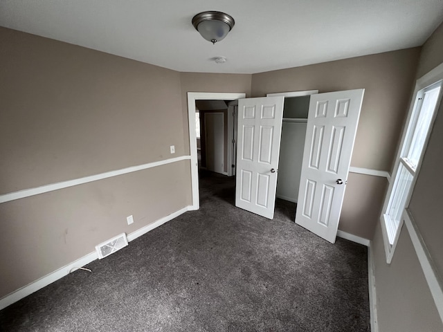 unfurnished bedroom with a closet and dark carpet