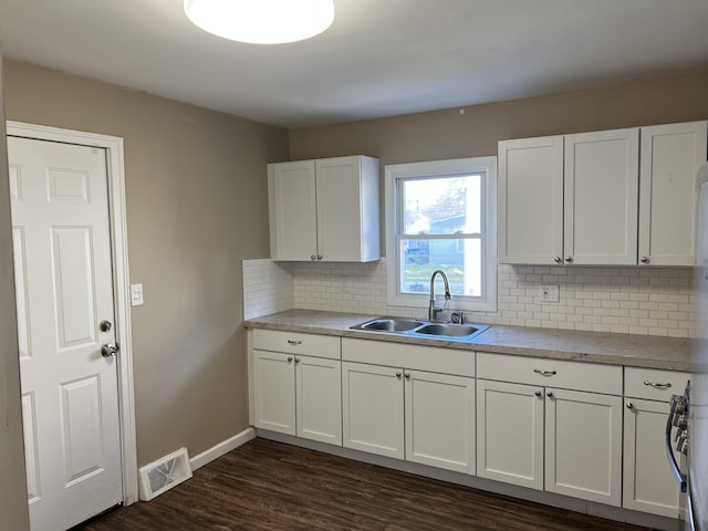 kitchen featuring decorative backsplash, stove, sink, white cabinets, and dark hardwood / wood-style floors