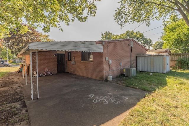 exterior space featuring a carport, a yard, a shed, and central AC unit