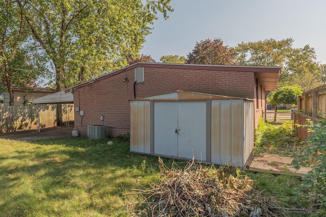 view of outdoor structure featuring a lawn and central AC unit