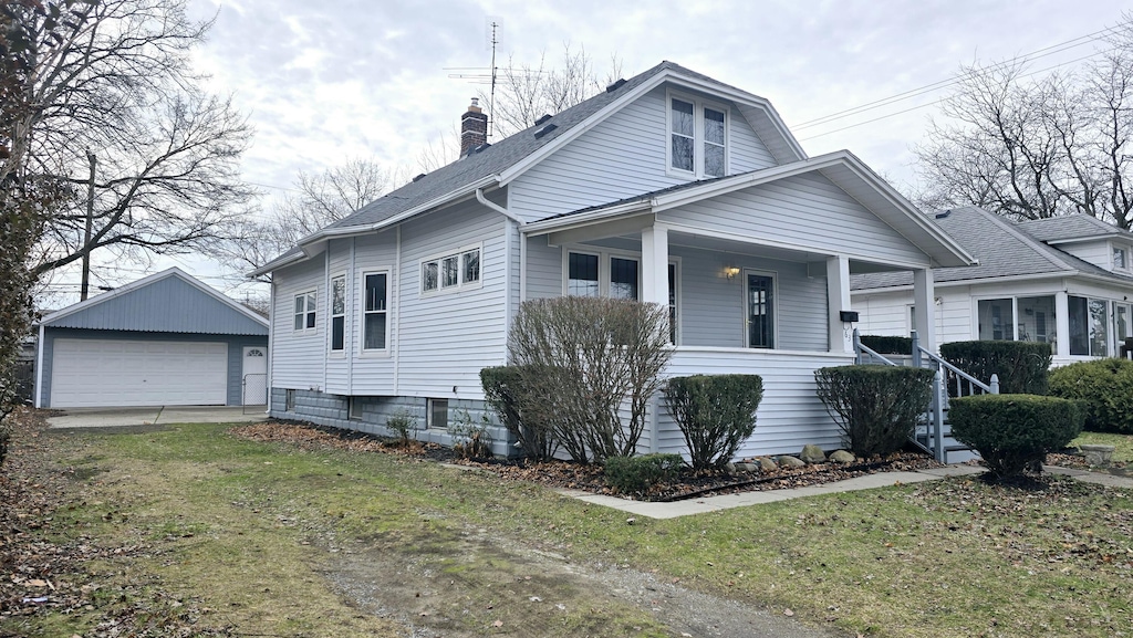 view of front facade with a porch, a garage, an outdoor structure, and a front lawn