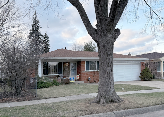 single story home with an attached garage, a shingled roof, concrete driveway, and brick siding