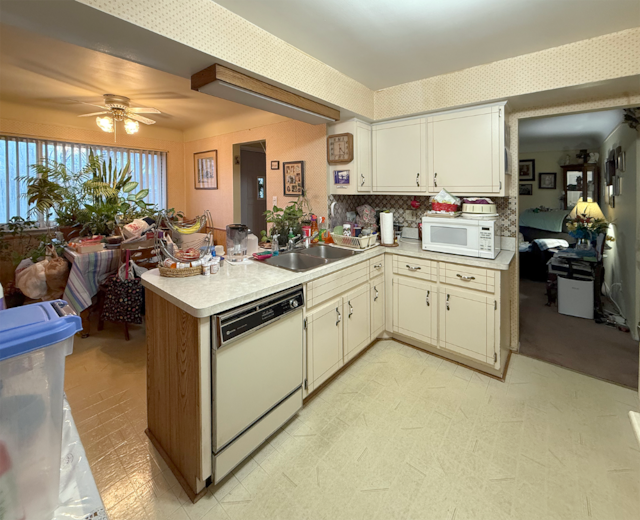 kitchen featuring a peninsula, white appliances, light countertops, and light floors