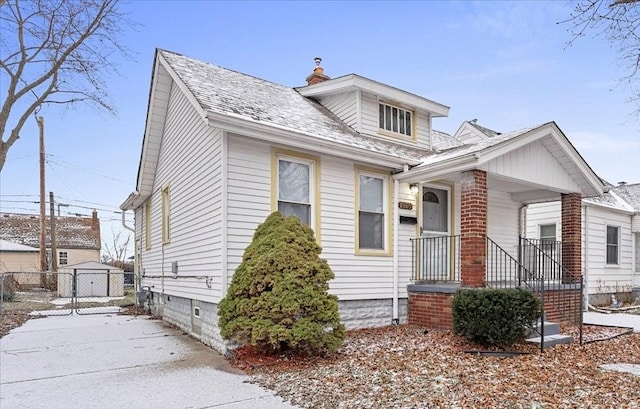 bungalow-style home with a porch and a storage shed