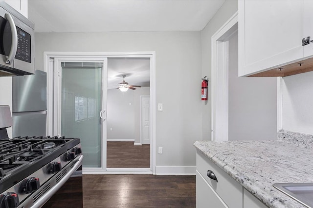 kitchen featuring white cabinets, appliances with stainless steel finishes, dark hardwood / wood-style floors, and light stone countertops