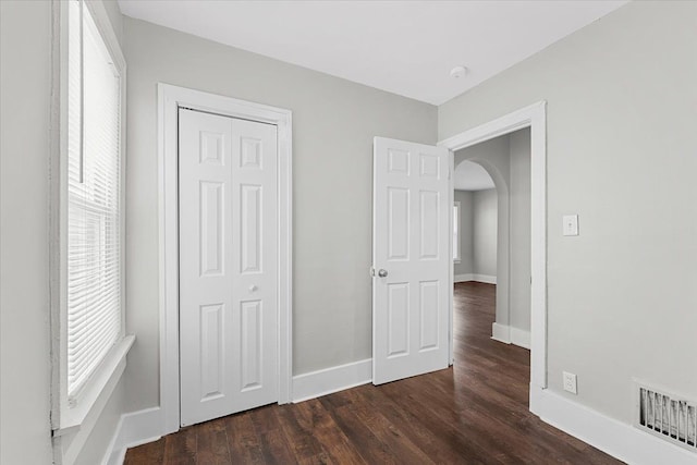 unfurnished bedroom featuring dark wood-type flooring and a closet