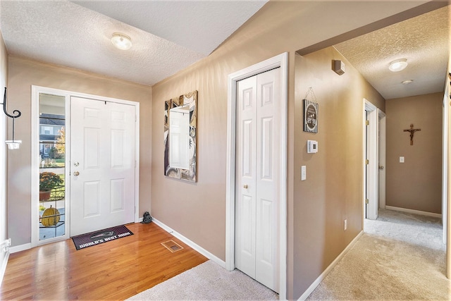 carpeted foyer entrance featuring a textured ceiling