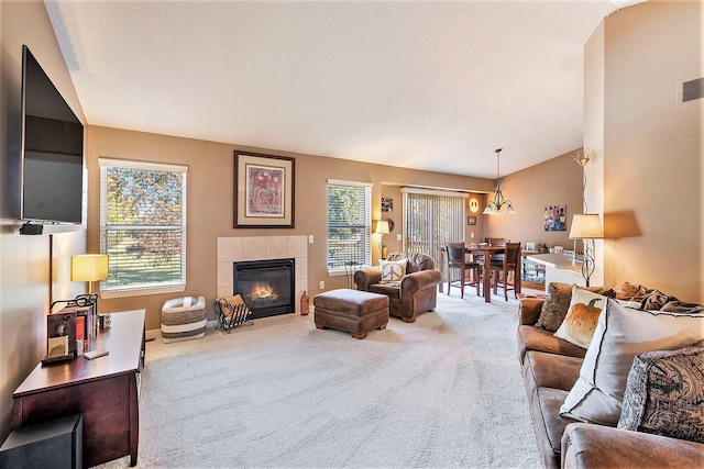 living room featuring carpet floors, a notable chandelier, lofted ceiling, and a tiled fireplace