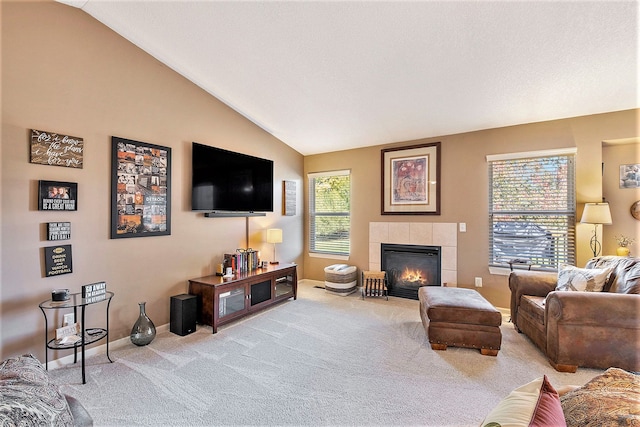 living room featuring lofted ceiling, a wealth of natural light, and a tiled fireplace