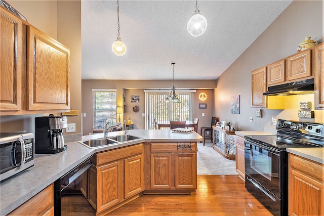 kitchen featuring pendant lighting, black appliances, sink, light wood-type flooring, and kitchen peninsula