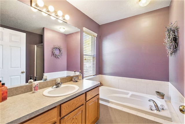 bathroom with vanity, shower with separate bathtub, and a textured ceiling