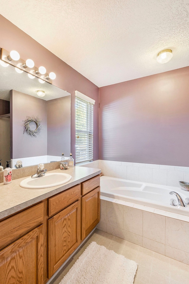 bathroom featuring tile patterned flooring, vanity, a relaxing tiled tub, and a textured ceiling