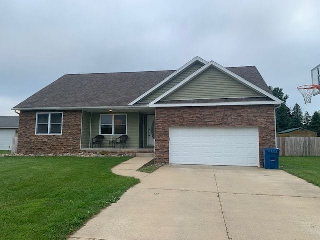 view of front facade with a front lawn, covered porch, and a garage