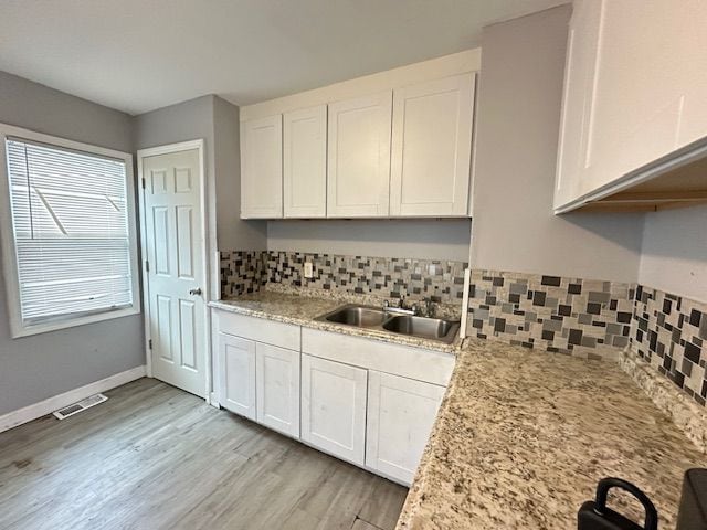 kitchen featuring white cabinetry, sink, light stone countertops, and light hardwood / wood-style flooring