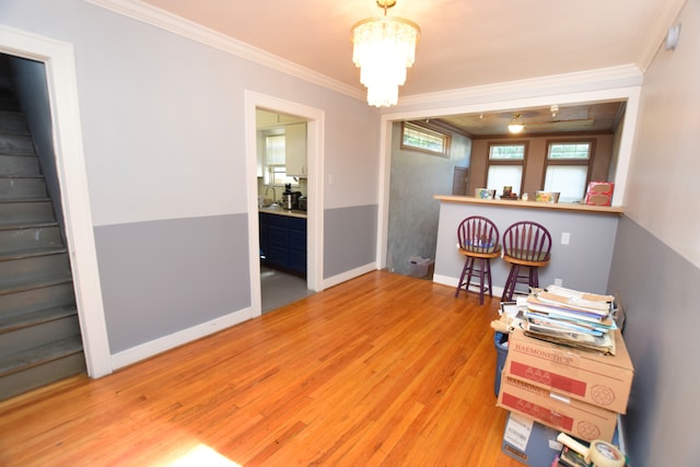 dining space with hardwood / wood-style flooring, crown molding, and a notable chandelier