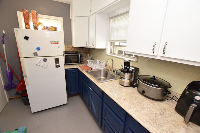 kitchen featuring blue cabinetry, white cabinetry, sink, white refrigerator, and backsplash