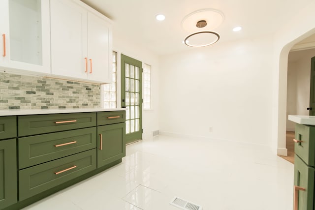 kitchen featuring white cabinets, decorative backsplash, light tile patterned floors, and green cabinets