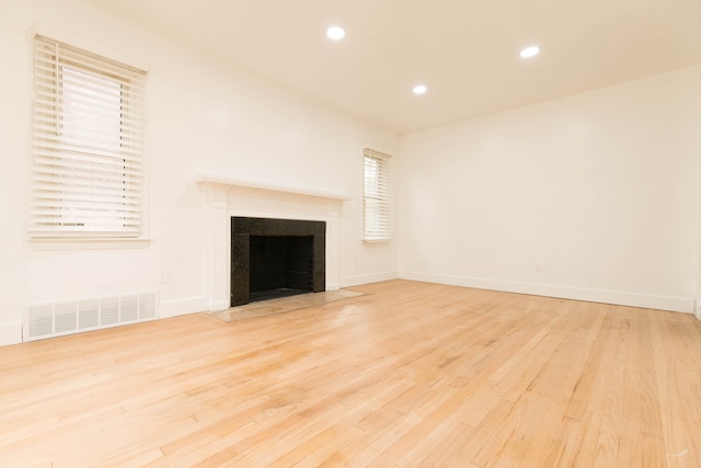 unfurnished living room with a tile fireplace and light hardwood / wood-style floors