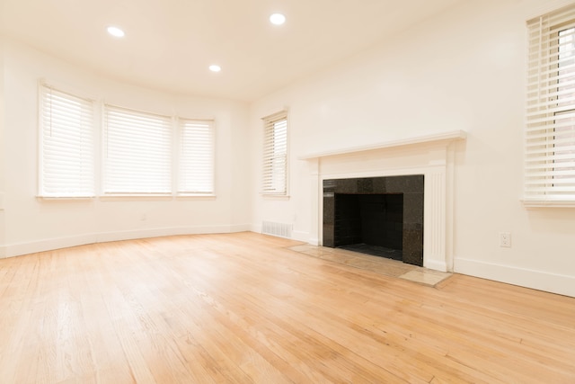 unfurnished living room featuring light hardwood / wood-style floors and a tiled fireplace