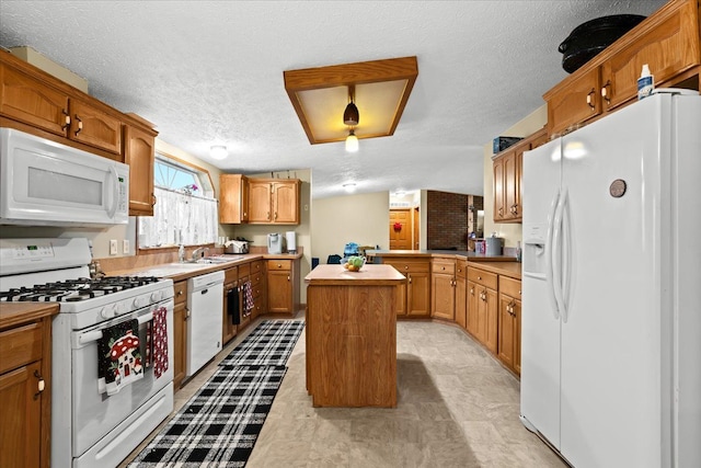 kitchen with a center island, sink, kitchen peninsula, a textured ceiling, and white appliances