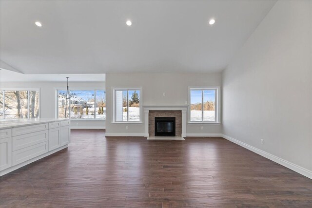 unfurnished living room with dark wood-type flooring, recessed lighting, vaulted ceiling, and baseboards