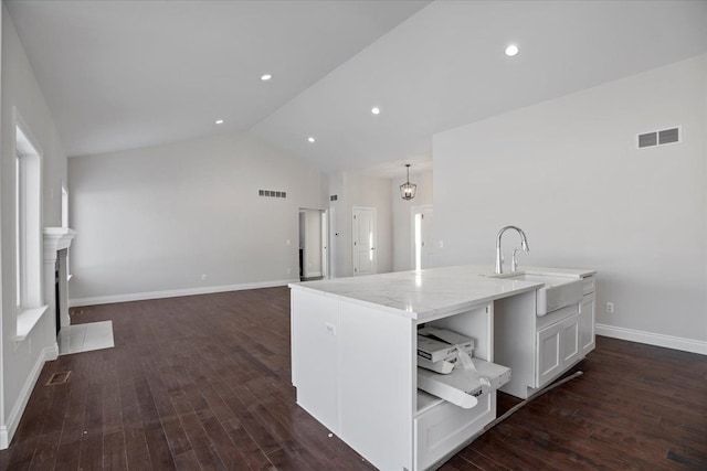 kitchen with a fireplace with flush hearth, lofted ceiling, visible vents, and a sink