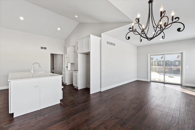 kitchen with dark wood-style floors, a kitchen island with sink, white cabinets, and visible vents