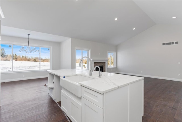 kitchen featuring dark wood finished floors, visible vents, a brick fireplace, open floor plan, and a sink