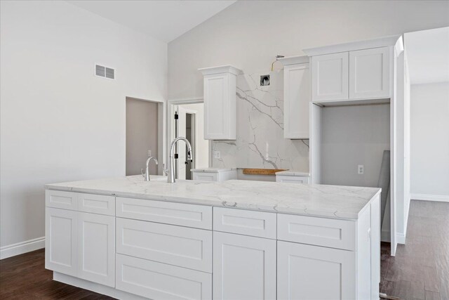 kitchen featuring lofted ceiling, dark wood-type flooring, a kitchen island, white cabinetry, and tasteful backsplash