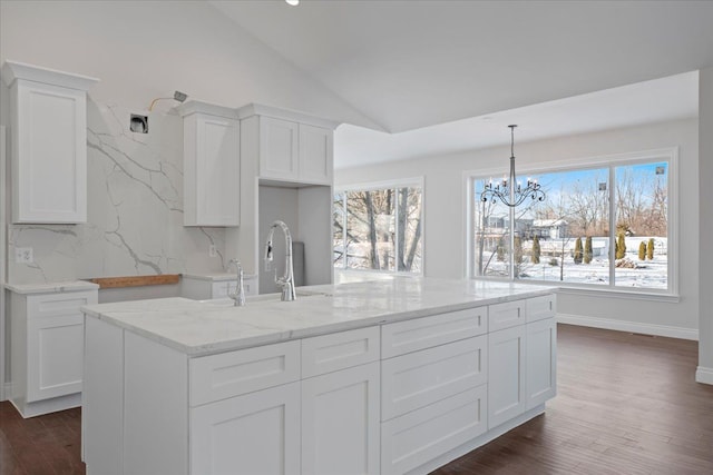 kitchen with decorative backsplash, dark wood-type flooring, vaulted ceiling, white cabinetry, and a sink