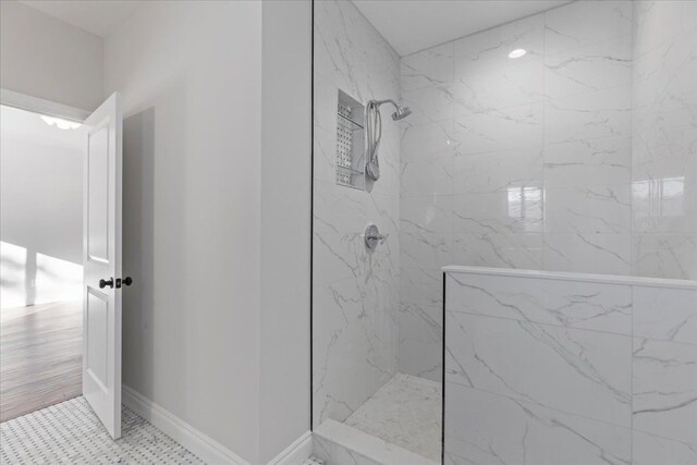 full bath featuring a marble finish shower and baseboards