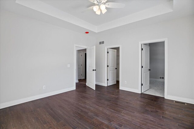 unfurnished bedroom featuring a tray ceiling, visible vents, and baseboards