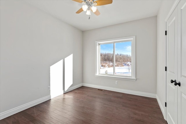 unfurnished bedroom with a ceiling fan, visible vents, dark wood finished floors, and baseboards