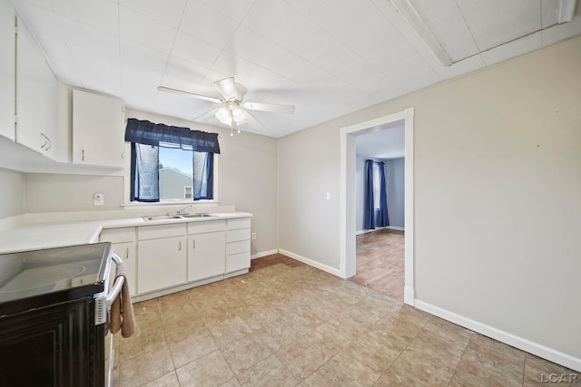 kitchen featuring white cabinets, stove, ceiling fan, and sink