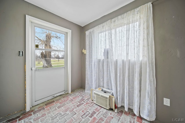 doorway to outside featuring a wall unit AC and a wealth of natural light