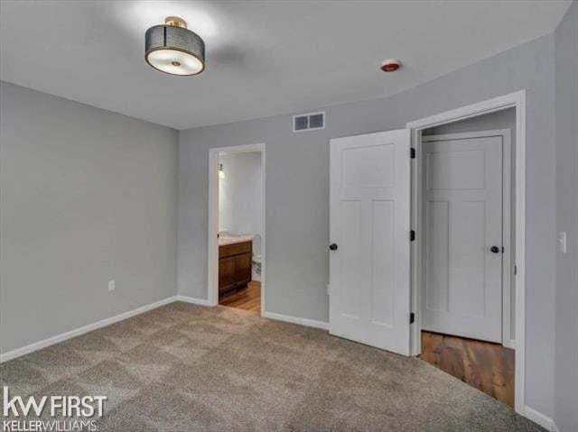 unfurnished bedroom with light colored carpet and connected bathroom