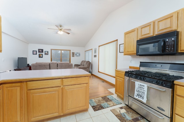 kitchen with light tile patterned floors, stainless steel range with gas cooktop, lofted ceiling, light brown cabinets, and backsplash