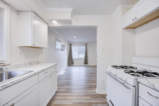 kitchen with white range with gas cooktop, white cabinetry, and light stone countertops