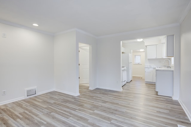 unfurnished living room featuring sink, light wood-type flooring, and ornamental molding