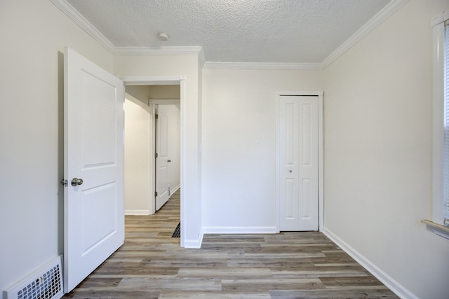 unfurnished bedroom featuring crown molding, a closet, light hardwood / wood-style floors, and a textured ceiling