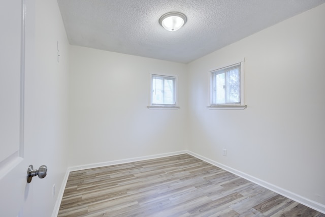 spare room featuring light hardwood / wood-style flooring and a textured ceiling