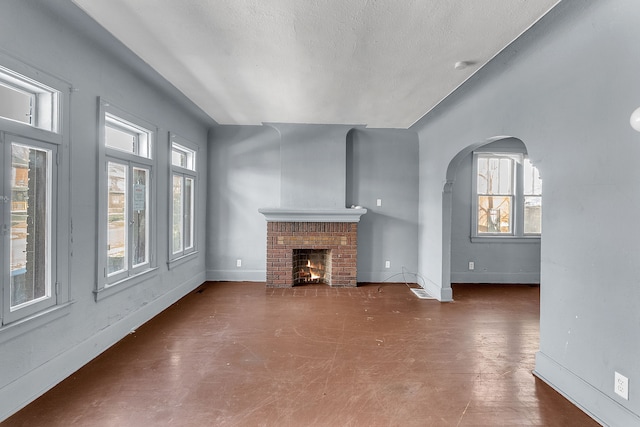 unfurnished living room with a fireplace, a healthy amount of sunlight, and a textured ceiling