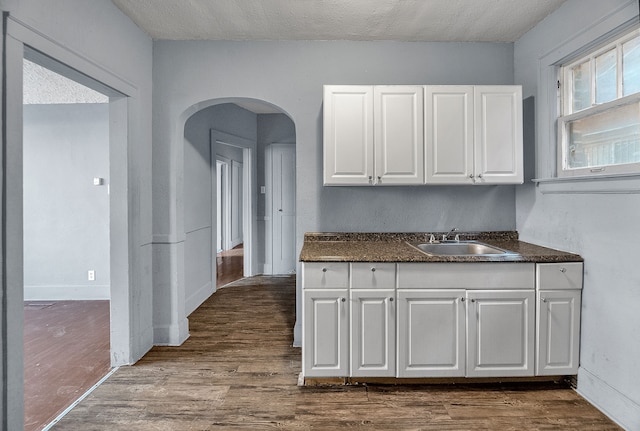 kitchen with white cabinets, hardwood / wood-style floors, a textured ceiling, and sink