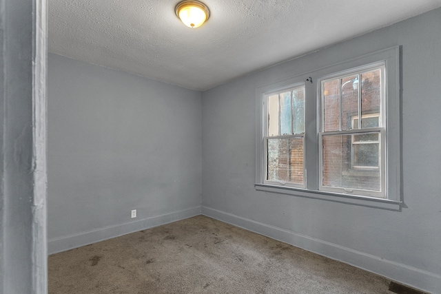 carpeted empty room with a textured ceiling