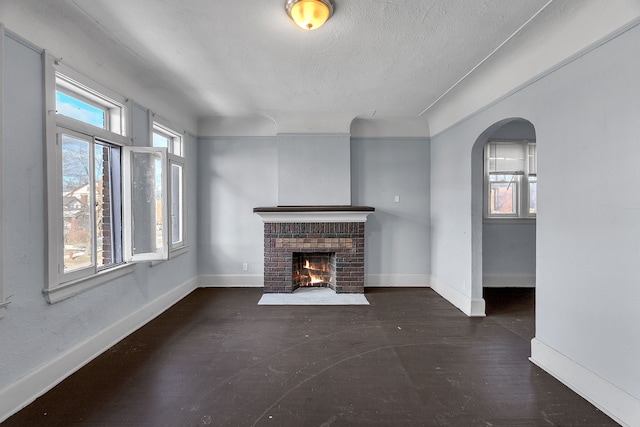 unfurnished living room with a textured ceiling and a brick fireplace